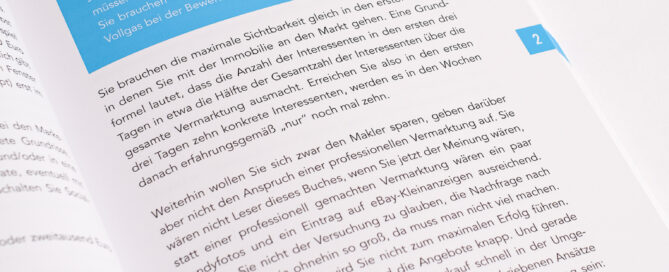 Offenes Buch mit weißem Papier, schwarzem Text und blauem Infokasten auf weißem Hintergrund.