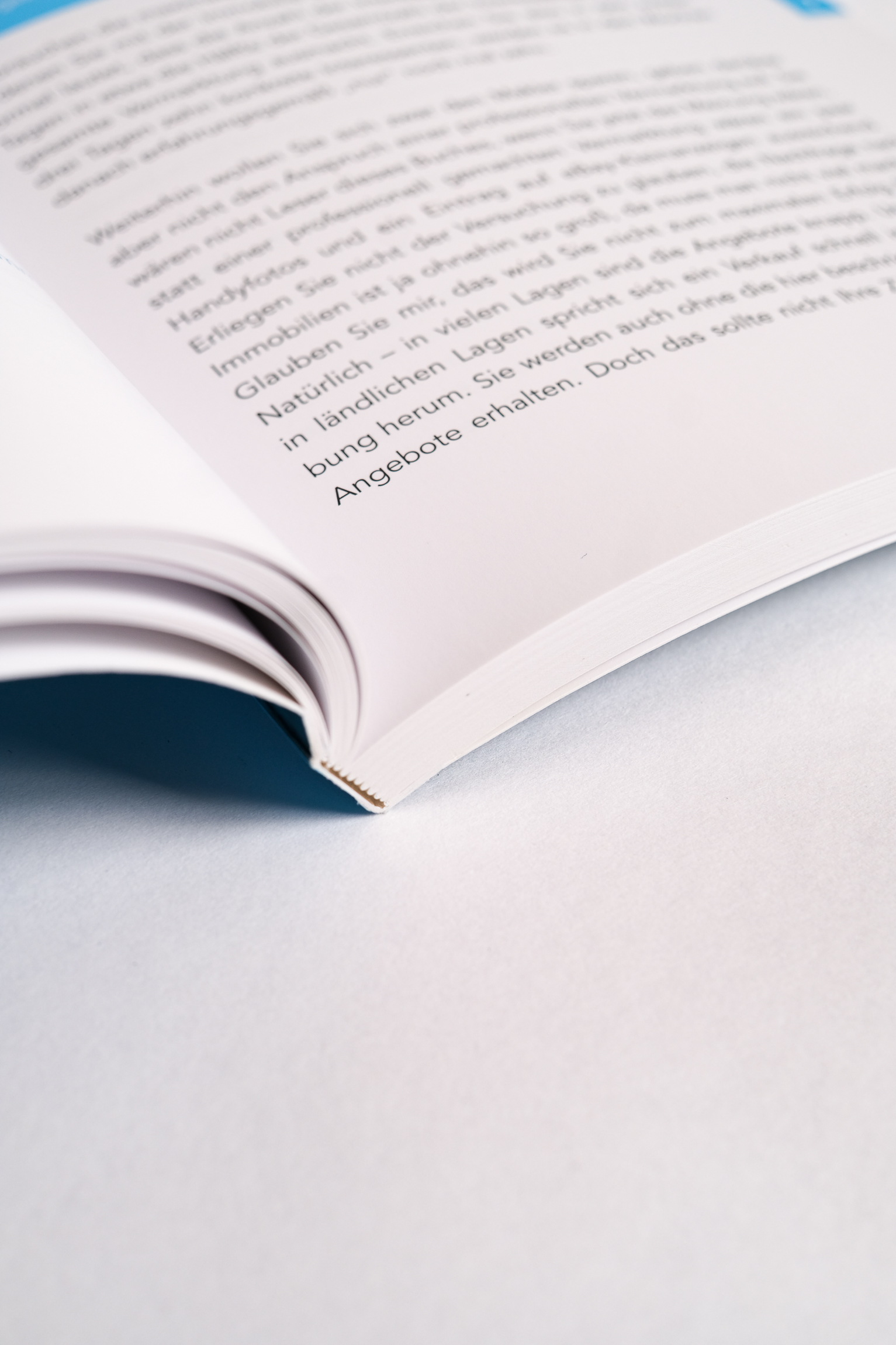Offenes Buch auf hellem Hintergrund Offenes Taschenbuch auf heller Fläche mit sichtbarem Text und weichem, natürlichem Licht.