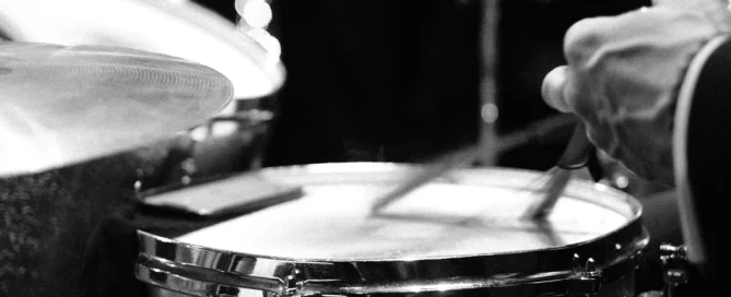 Schwarzweißfoto eines Schlagzeugers beim Spielen von Snare und Hi-Hat auf einer Bühne.