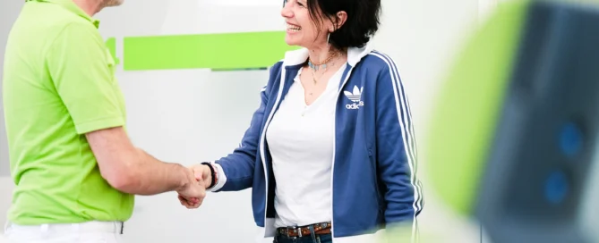 Freundliches Handshake zwischen Patientin und Arzt in moderner medizinischer Praxis in Würzburg.
