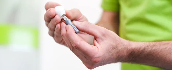 Hand hält eine Zahn-Implantat-Modell in einer medizinischen Umgebung, Fokus auf Gerät und Hände.