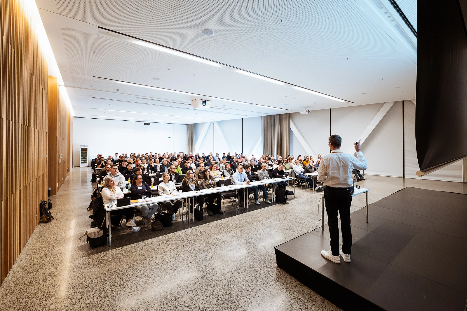 Moderner Business-Workshop mit rednerischer Präsentation in Deutschland Moderator bei modernem Business-Event in Würzburg, hält Präsentation vor engagiertem Publikum.