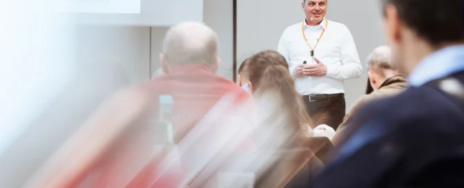 Mann hält Präsentation vor engagiertem Publikum bei Business-Event in Würzburg.