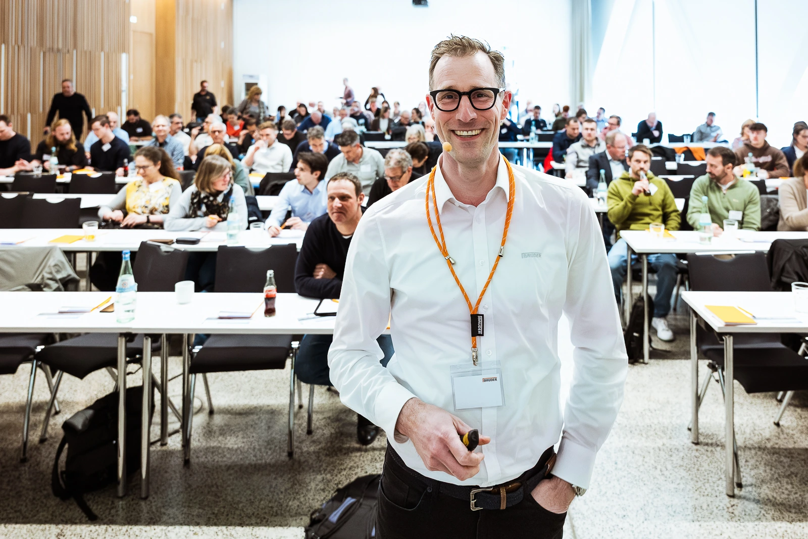 Business-Event in Würzburg: Motivierter Redner und Teilnehmer Mann beim Business-Event in Würzburg, spricht mit Teilnehmern vor einem Konferenzraum.