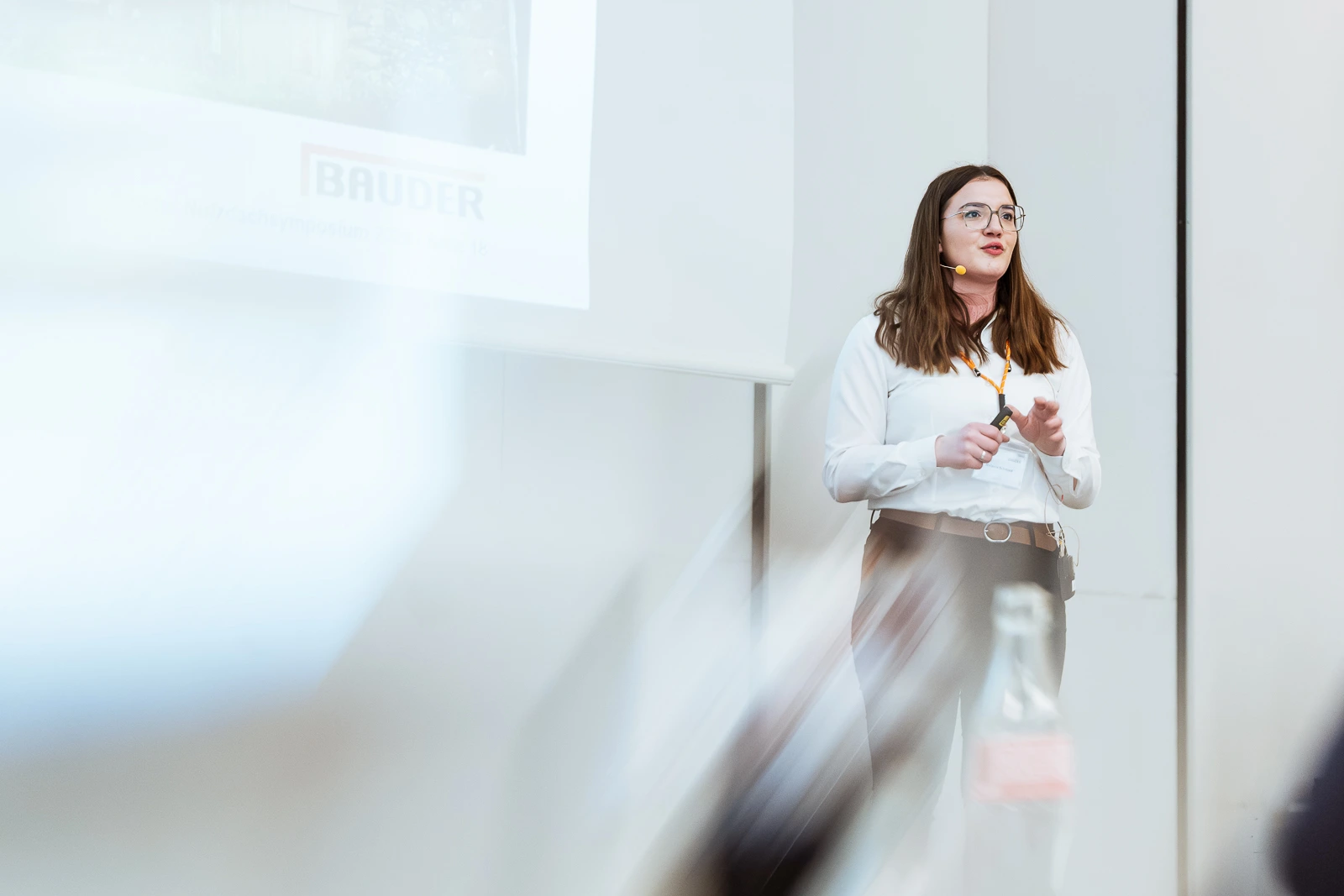 Professionelle Präsentation einer jungen Fachfrau in modernem Raum Junge Frau hält Präsentation in modernem Konferenzraum, vor weißer Projektionswand, in Würzburg.
