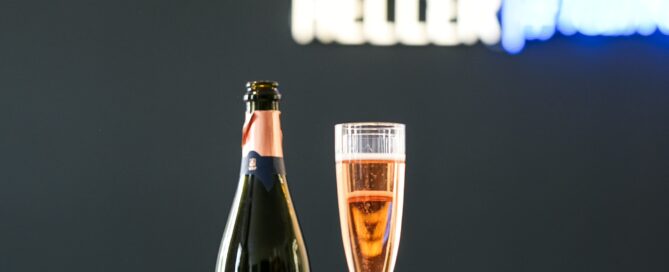 Elegantes Business-Interior mit Sekt, Notizen und beleuchteter Firmenbeschilderung im Hintergrund.