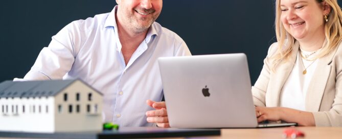 Johannes Heller und Mitarbeiterin bei einer Besprechung mit Immobilienmodell und Laptop in modernem Büro in Würzburg.