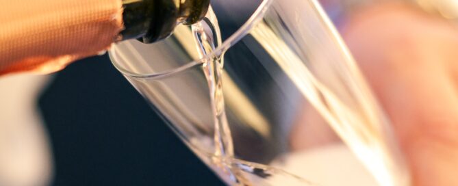 Champagner wird in ein elegantes Glas gegossen, mit Fokus auf Dekoration, Genuss und festliche Atmosphäre.