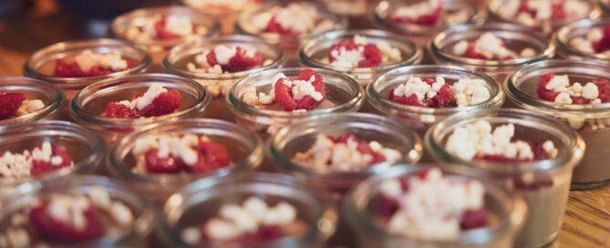 Mehrere Gläser mit Dessert, cremig und mit Beeren, auf Holzplatte bei Veranstaltung in Würzburg