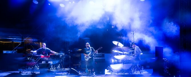 Moses Yoofee Trio bei einem Konzert im blauen Bühnenlicht beim Hafensommer Würzburg.