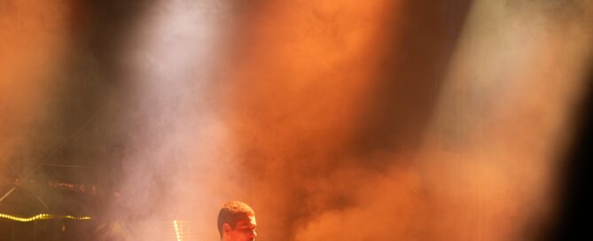 Keyboarder des Moses Yoofee Trios beim Hafensommer-Konzert in Würzburg unter orangefarbenem Bühnenlicht.