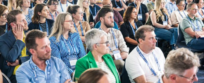 Aufmerksames Publikum bei einer Konferenz in Würzburg, teilweise applaudierend.
