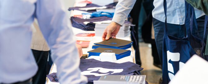 Teilnehmer betrachten Kleidung und Infomaterial am Messestand der FORM.CYCLE CONNECT in Würzburg.