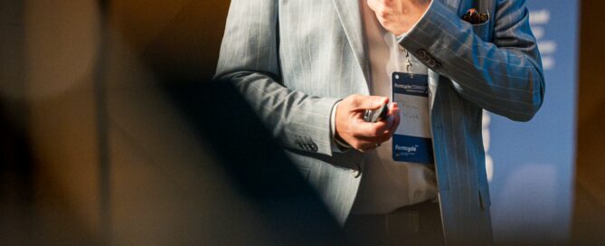 Eventfotografie in Würzburg: Referent im Anzug spricht mit Headset vor Publikum.