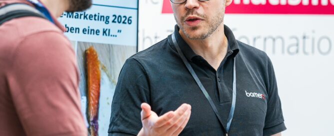 Zwei Männer im Gespräch an einem Messestand bei einer Fachveranstaltung in Würzburg.